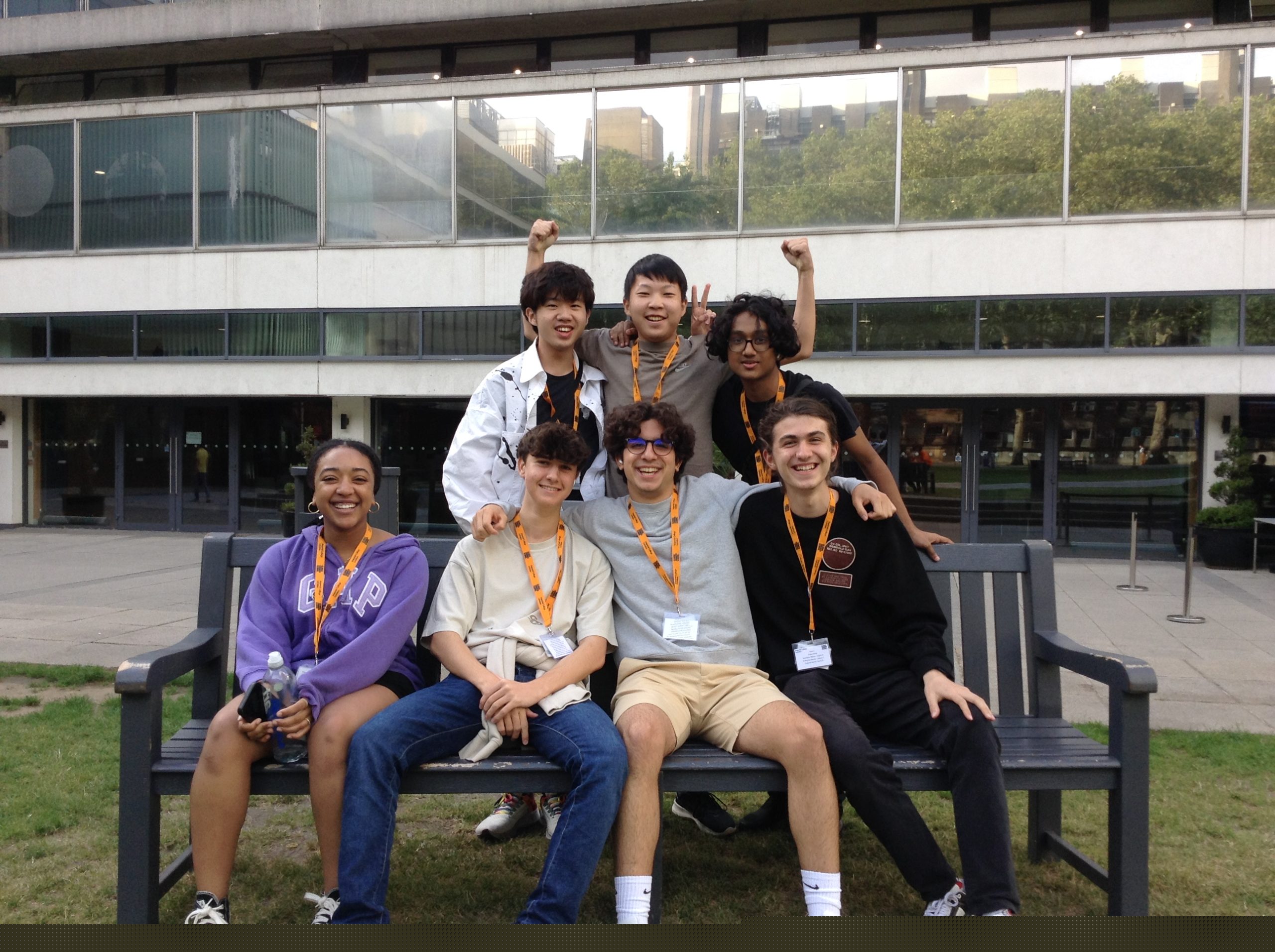 Large group of students post around a chair on the front lawn